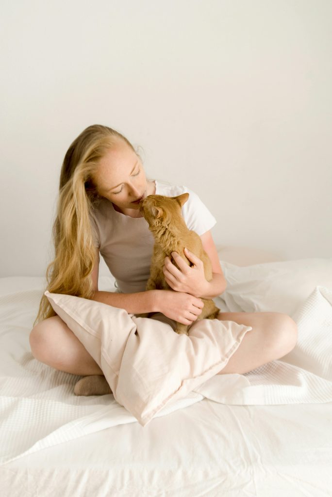 Blonde woman sitting and hugging cat